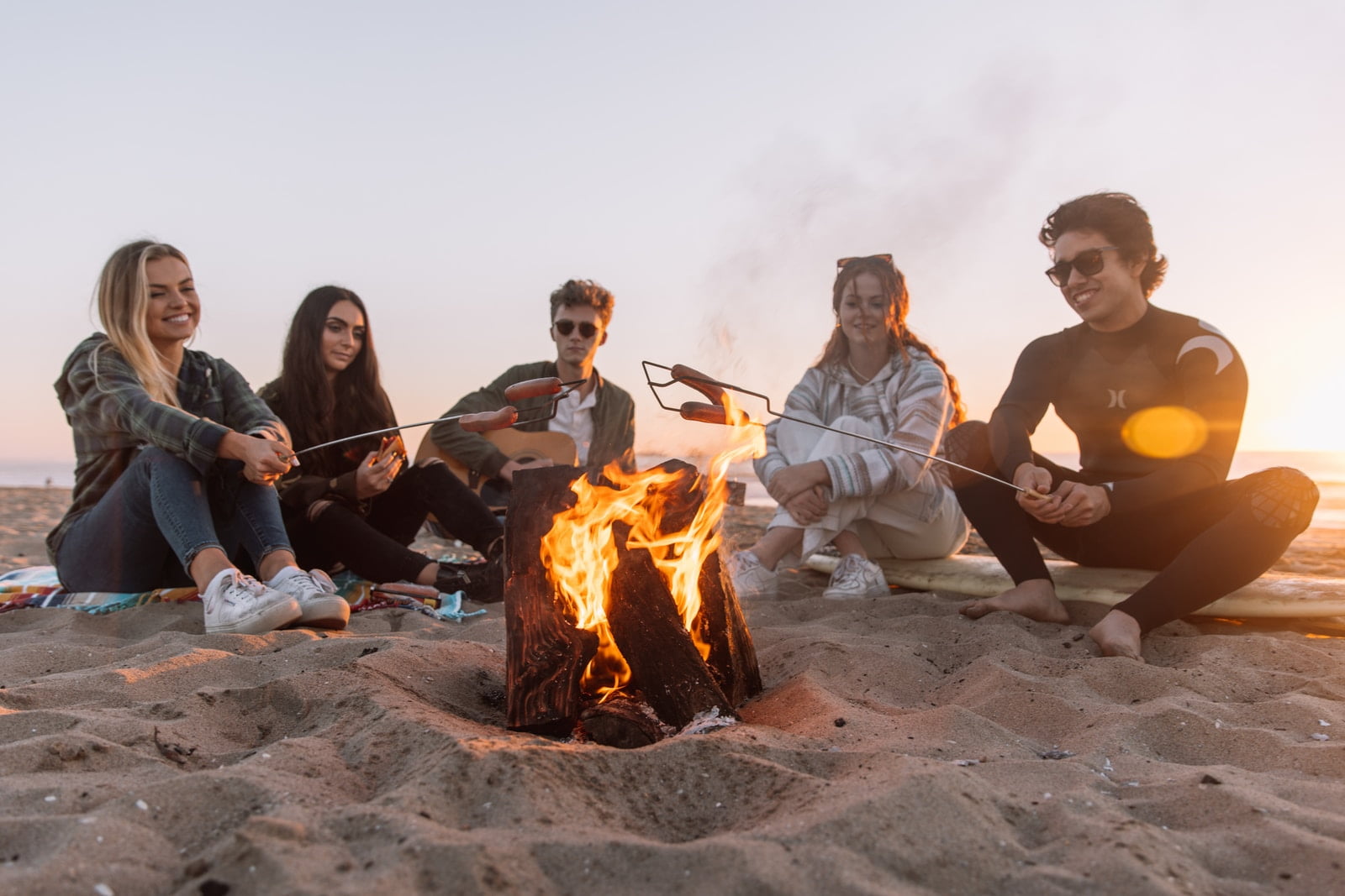 Photo by Ball Park Brand group of people sitting on ground with bonfire